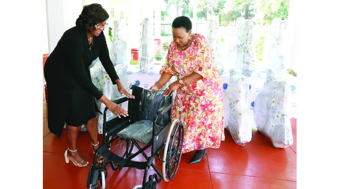 Mrs Priscilla Zvobgo hands over one of the wheelchairs to Angel of Hope Foundation patron First Lady Dr Auxillia Mnangagwa on behalf of IDBZ at Zimbabwe House yesterday