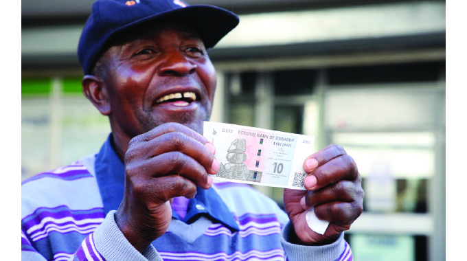 Pensioner Mr Steven Makanga admires a 10 ZiG note after withdrawing cash from a bank in the Central Business District of Harare yesterday