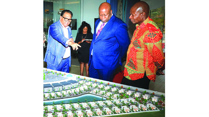 Local Government and Public Works Minister Winston Chitando (centre) and his counterpart National Housing and Social Amenities Minister Daniel Garwe (right) listen to Mulk Holdings International Chairman Mr Shaji UI Mulk explain the features on the artistic impression of the Zimbabwe Cyber City at the official opening of a marketing office in Mt Hampden yesterday.