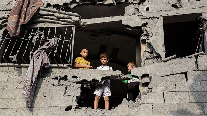 Palestinian boys stand in a damaged building after Israeli airstrikes in the Southern Gaza Strip city of Khan Younis, Oct. 25, 2023. Photo: Xinhua by Rizek Abdeljawad.