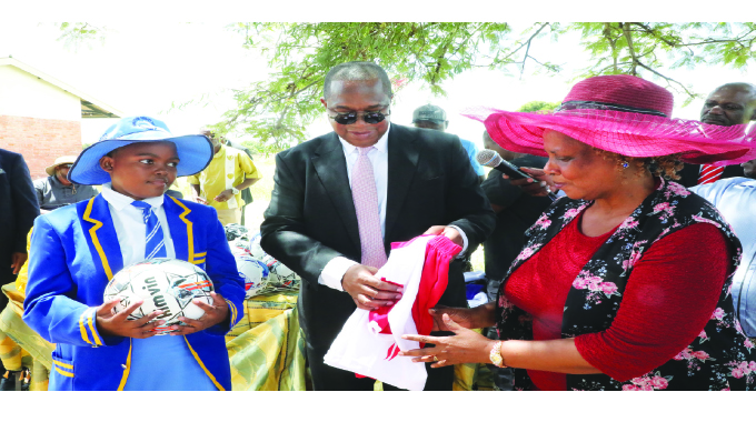 Finance, Economic Development and Investment Promotion Minister Mthuli Ncube presents soccer kits and a soccer ball to Mahlathini Primary School headmistress Mrs Ruth Phiri and the school’s pupil Nomuhle Ngwenya at Mkhithika Thebe Primary School in Cowdray Park yesterday